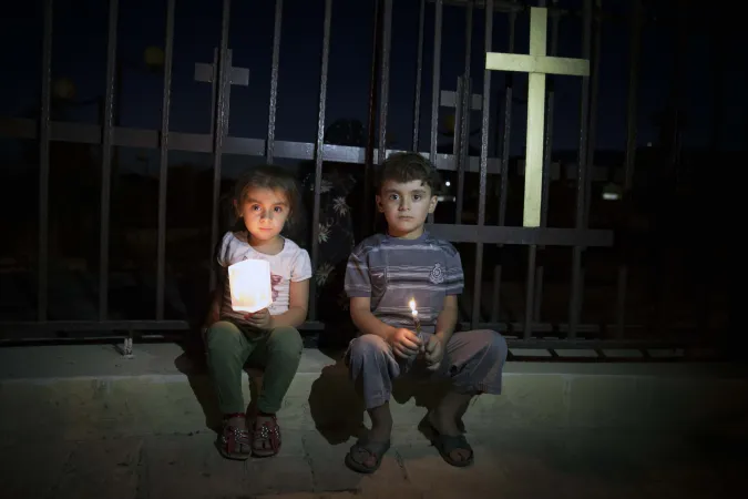 Aus dem Irak geflohene Kinder sitzen neben einer Marienstatute. Die beiden jungen Christen kommen aus Mosul, einer früher christlich geprägten, die vom Islamischen Staat "ethnisch gesäubert" wurde. 