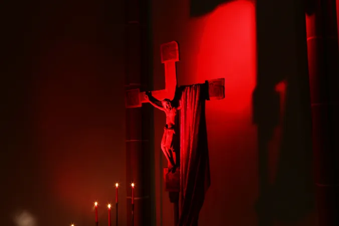 Rot erleuchtetes Kreuz bei einem Gebetsabend für verfolgte Christen von "Kirche in Not".
