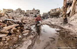 Ein Mann fährt durch zerstörte Häuserzeilen in Aleppo (Syrien). / Ismael Martinez Sanchez / Kirche in Not