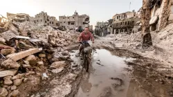 Ein Mann fährt durch zerstörte Häuserzeilen in Aleppo (Syrien). / Ismael Martinez Sanchez / Kirche in Not