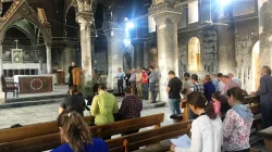 Gläubige beim Gebet in der ausgebrannten Kirche.  / Kirche in Not