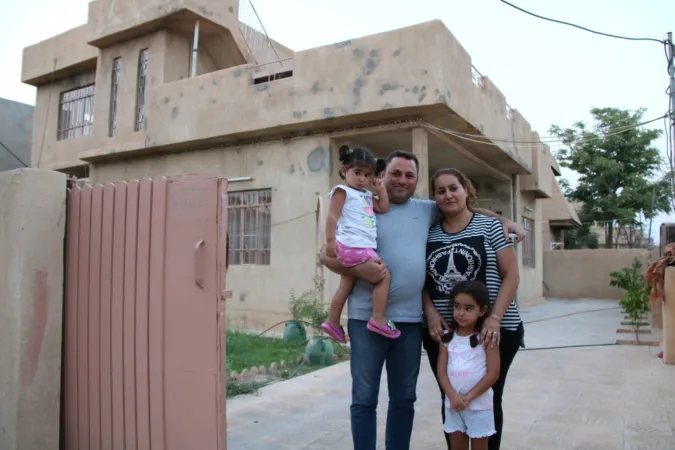 Eine christliche Familie vor ihrem notdürftig renovierten Haus in Karakosch.
