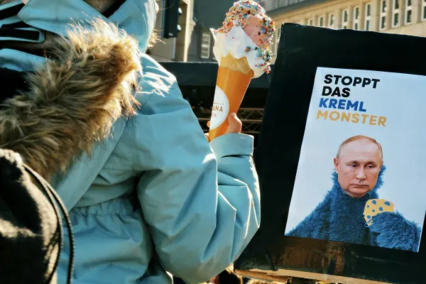 “Stopp das Kreml-Monster”: Ein Plakat auf einer Demonstration gegen Russlands Invasion der Ukraine stellt Wladimir Putin als unersättliches “Krümel-Monster” der Muppet-Show dar, der einen blau-gelben Keks verspeisen will.  / Psychedelic Lulo / Unsplash (CC0) 