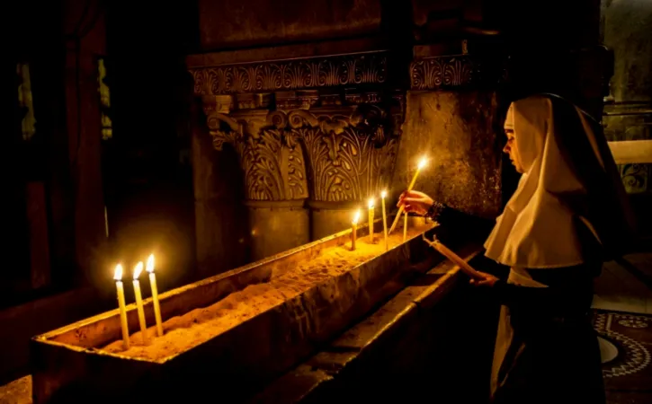 Ordensfrau entzündet Kerzen in der Grabeskirche.