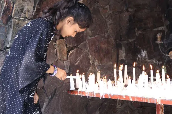 Ein junges Mädchen entzündet eine Gebetskerze in einem marianischen Schrein in Pakistan / Magdalena Wolnik