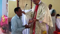 Bishof George Pallipparambil von Miao gibt einem Pfarreimitglied ein Neues Testament / Bistum Miao