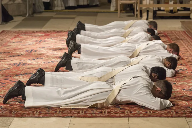 Die Priesteramtskandidaten liegen vor dem Altar