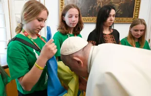 Papst Franziskus küsst am 3. August 2023 in Lissabon eine ukrainische Flagge / Vatican Media