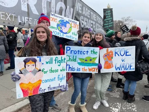 Junge Erwachsene halten bunte Schilder vor dem Obersten Gerichtshof der USA beim Marsch für das Leben in Washington, D.C., am 21. Januar 2022. 
