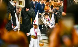 Ein als Nazarener gekleideter Junge verfolgt die Prozession in Sevilla in der Karwoche 2024. / Joacquín Carmona
