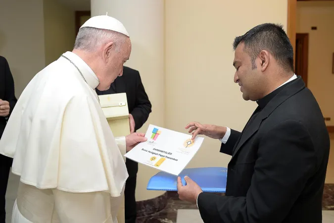 Papst Franziskus erhält von Pfarrer Regamy Thillainathan, Direktor für Berufungspastoral in Köln, die Urkunde.