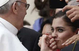 Eine junge Frau küsst die Hand von Papst Franziskus. / (C) Pax Press Agency, SARL, Geneva