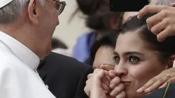 Eine junge Frau küsst die Hand von Papst Franziskus. / (C) Pax Press Agency, SARL, Geneva