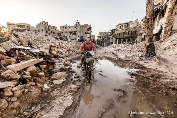 Ein Mann fährt durch zerstörte Häuserzeilen in Aleppo (Syrien).