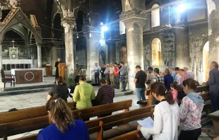 Gläubige beim Gebet in der ausgebrannten Kirche.  / Kirche in Not