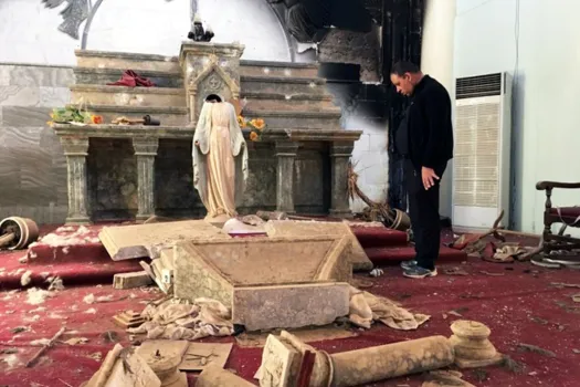 Priester im Altarraum seiner zerstörten Kirche in Karamles (Irak). / (C) Kirche in Not