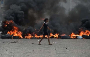 Eine Frau läuft an brennenden Barrikaden vorbei, die gegen Präsident Jovenel Moise protestierende Demonstranten am 10. Februar in Port-au_prince errichtet haben.  / Hector Retamal / AFP  Getty Images 