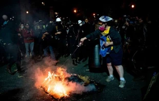 Eine Demonstrantin versucht ein von anderen Aktivisten entzündetes Feuer zu löschen: Portland am 31. Juli 2020. / Alisha JUCEVIC / AFP via Getty
