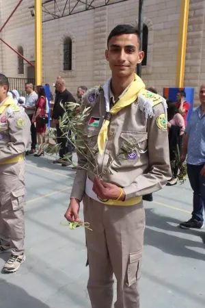 Suhail Abu Dawod in Pfadfinderuniform hält in der einen Hand einen Olivenzweig und in der anderen ein Palmblatt, das zu einem Kreuz geflochten ist. Das Foto stammt vom Palmsonntag 2023. Heute sagt Abu Dawod: „Wir bitten Gott um Frieden, um den Frieden, der sich seit der Auferstehung Jesu in der Welt ausbreitet. Meine inbrünstigen Gebete sind der Gerechtigkeit und der Schaffung eines dauerhaften Friedens im Heiligen Land gewidmet, besonders in unserer Stadt Gaza.”