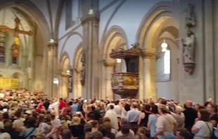 Während der etwa 45-minütigen Unterbrechung nutzten viele Anwesende ihre Handys, um Musik über die Audioanlage des Doms zu übertragen – es wurde gesungen und geklatscht. / Screenshot vom NDR